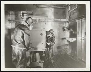 All-Weather Laboratory. Brooklyn, N.Y.--In this stainless steel room two warmly dressed men test an anti-aircraft director. The room is the Sperry Gyroscope Company's all-weather laboratory which the company built a year ago so that could test equipment under weather conditions from severest cold to greatest heat. The room is never made colder than 50 degrees below zero or hotter than 150 degrees, stainless steel was used in its construction corrosion-proof, and resistant to damage ultraviolet rays, used occasionally to simulate torrid sunlight. The test shown above is being conducted in Arctic weather so the men wear helmets and heavy flying suits.