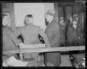 Men gathered inside of a room wearing coats, one of which is Councilman Robert Gardiner Wilson