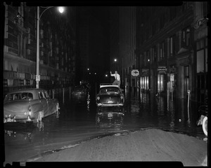 Flooded street with a man on top of a car outside of Compton Sandwich Shoppe